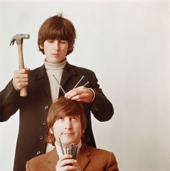 an odd image in which Beatles band member George Harrison mimicks hammering a nail on top of bandmate John Lennon's head